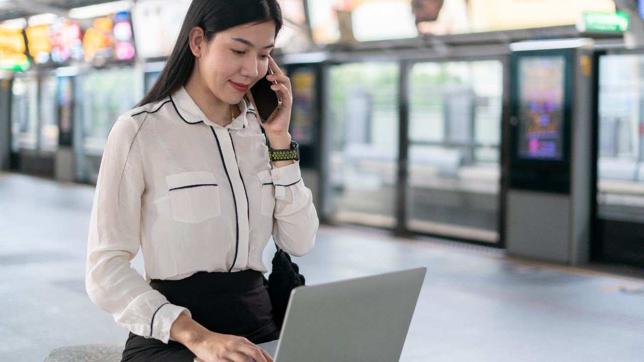 Asian woman on laptop and talking on smartphone