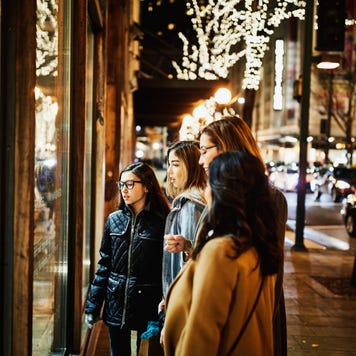 Two mature women and teenage daughters window shopping during holidays - stock photo