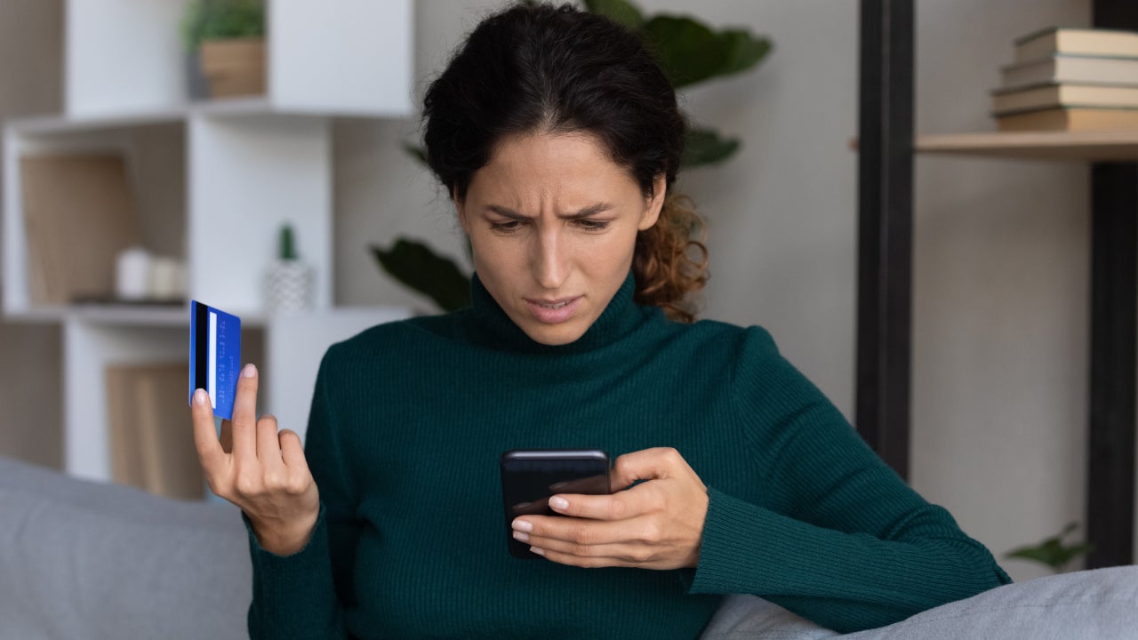 Concerned lady looking on smartphone having finance stolen from card