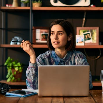 Woman sitting at a desk in front of a grey laptop