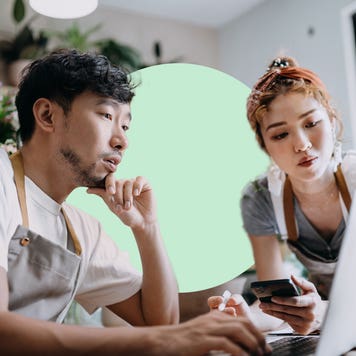 An Asian man and woman review a laptop.