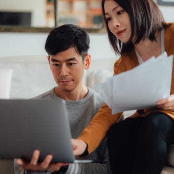 Young couple discussing over financial bills while using laptop on sofa