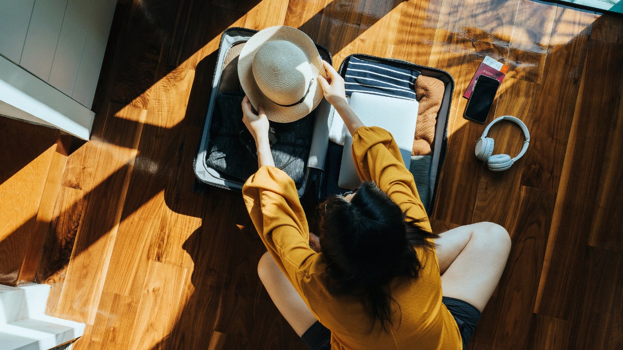 Overhead view of young Asian woman packing a suitcase for a trip