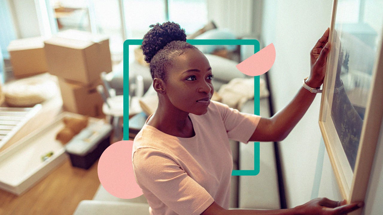 Black woman hanging a photograph on a wall