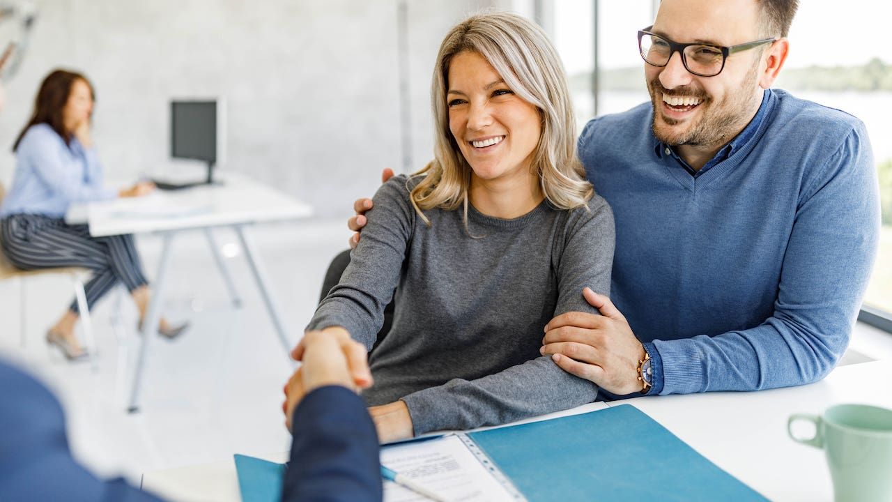 defeasance clause - couple shaking hands with bank officer, signed papers on desk