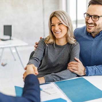 defeasance clause - couple shaking hands with bank officer, signed papers on desk