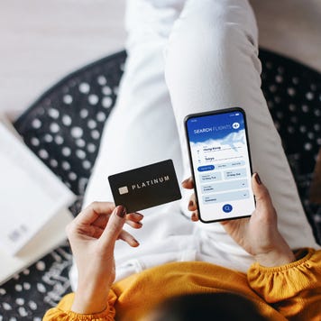 Woman booking flight tickets on airline website online with smartphone and making payment with credit card at home