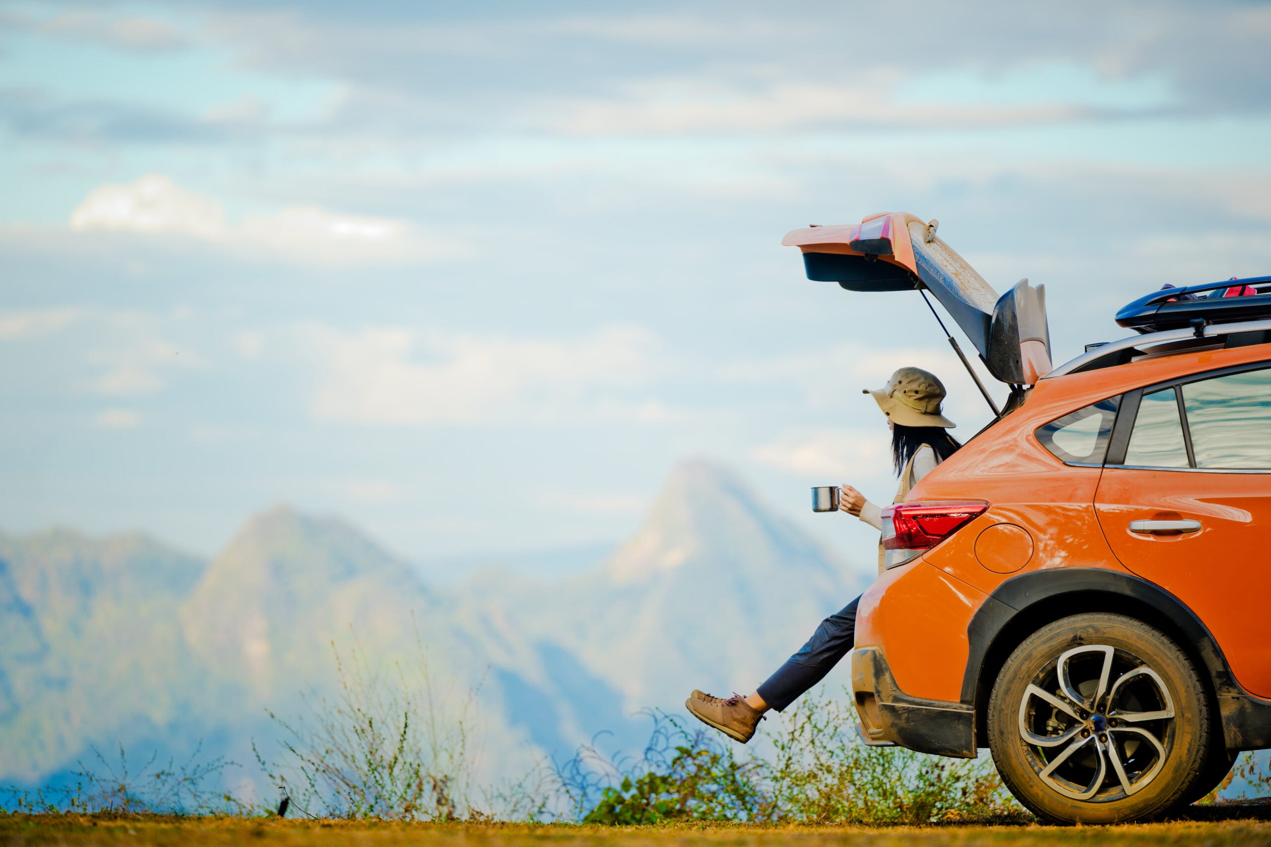 Female traveler enjoying the scenic view on the peak of mountain while sipping coffee