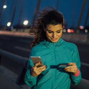 Athletic woman using credit card and mobile phone