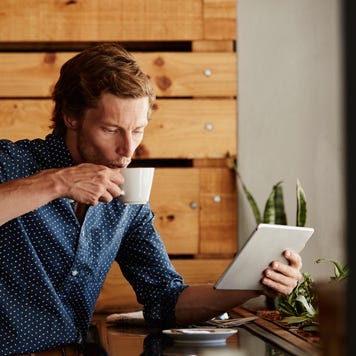 Man using tablet PC while having coffee at cafe