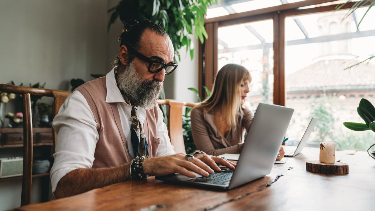 A couple of adults are working with laptops