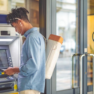 Young man getting cash out of ATM