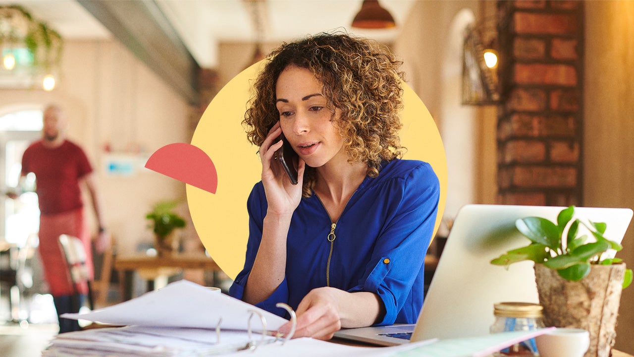 A woman talks on the phone while looking at paperwork.