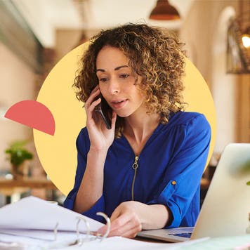 A woman talks on the phone while looking at paperwork.