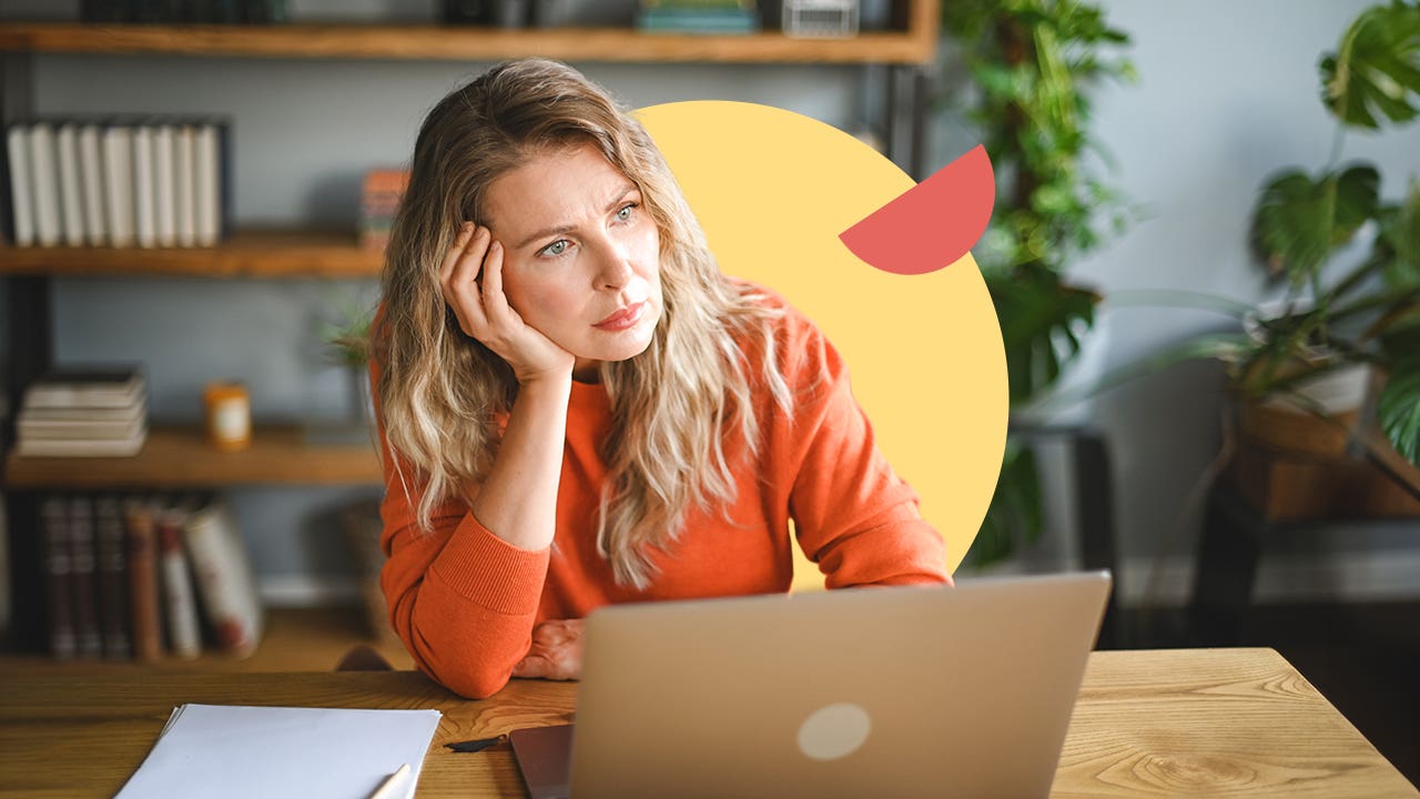 A white woman sitting in front of a laptop at a table looking thoughtful. There is an illustrated element of a yellow circle behind her and a small red half circle on it.