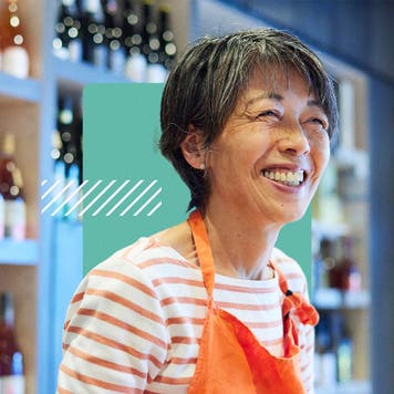 A shop owner wearing an apron smiles.