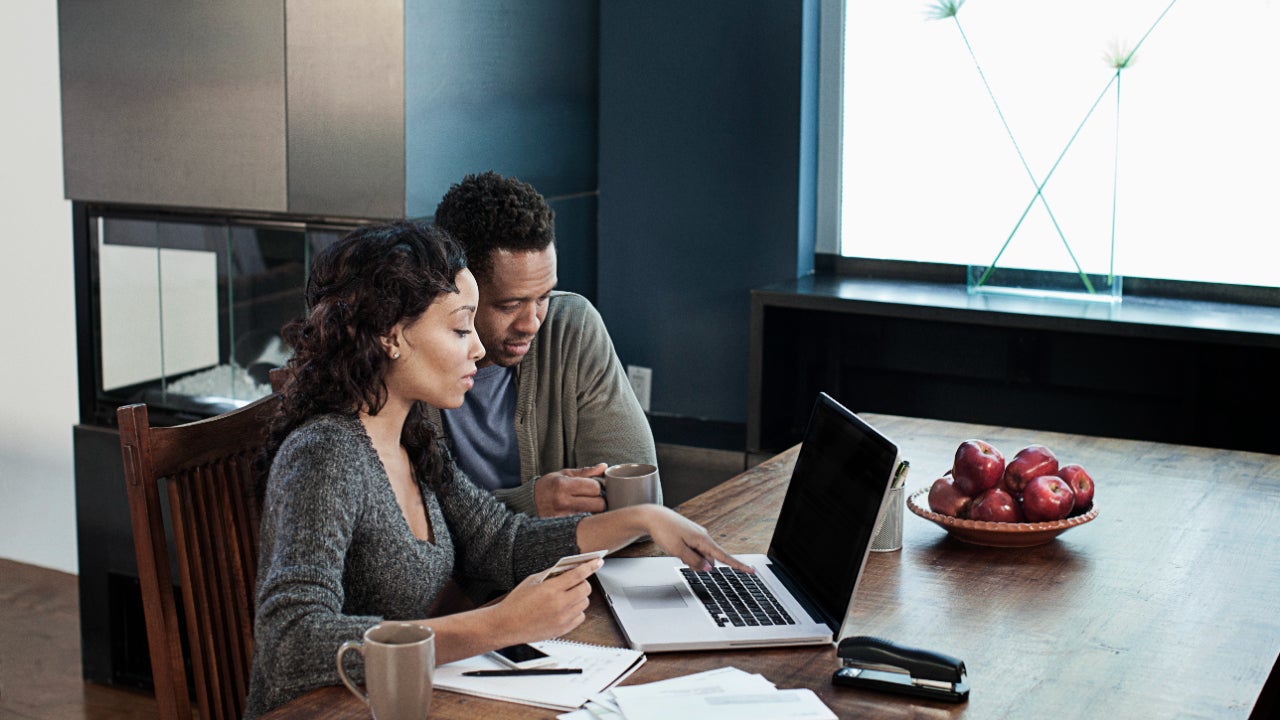 Woman using laptop while husband drinks coffee