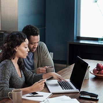 Woman using laptop while husband drinks coffee
