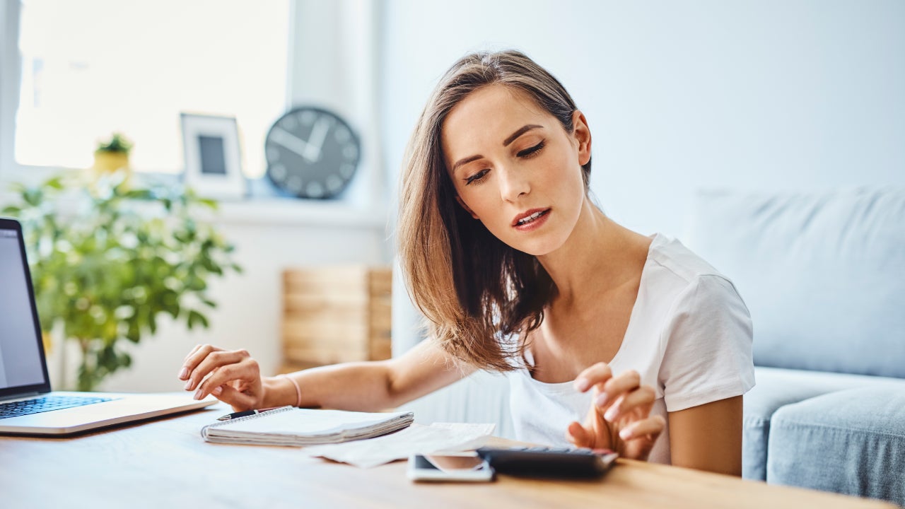 Young woman preparing home budget, using laptop and calculator