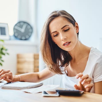 Young woman preparing home budget, using laptop and calculator