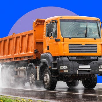 A dump truck is driven along a wet stretch of road.