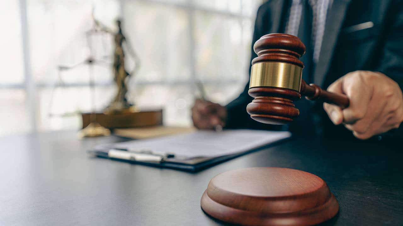 Lawyer working on contract documents and golden goddess scales with hammer on table providing advice.