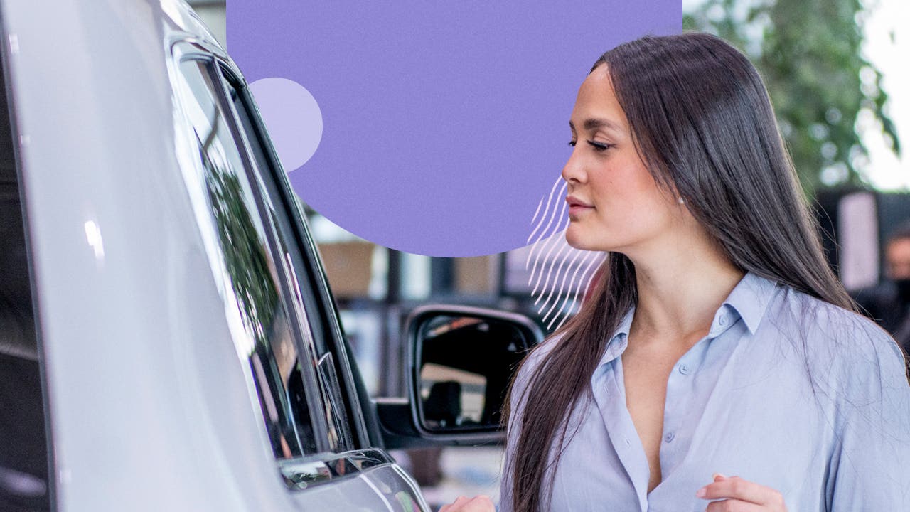 A white woman inspects a car at a dealership.