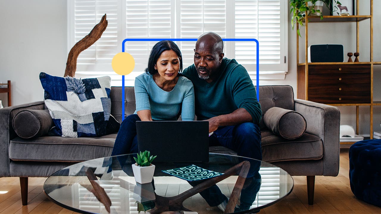 Couple sitting on a couch in front of a laptop