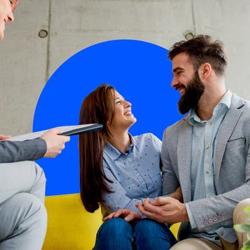 A couple stare lovingly at one another while sitting on a couch.