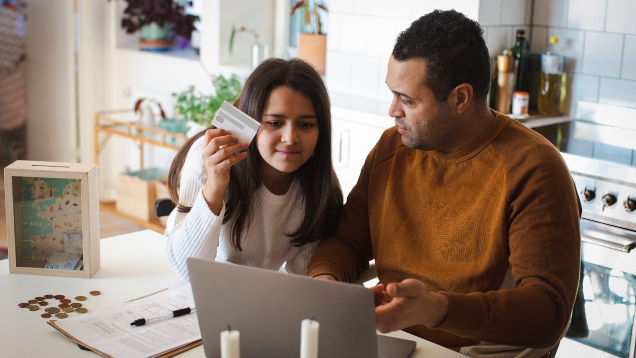 Father teaching online shopping to daughter on laptop at home