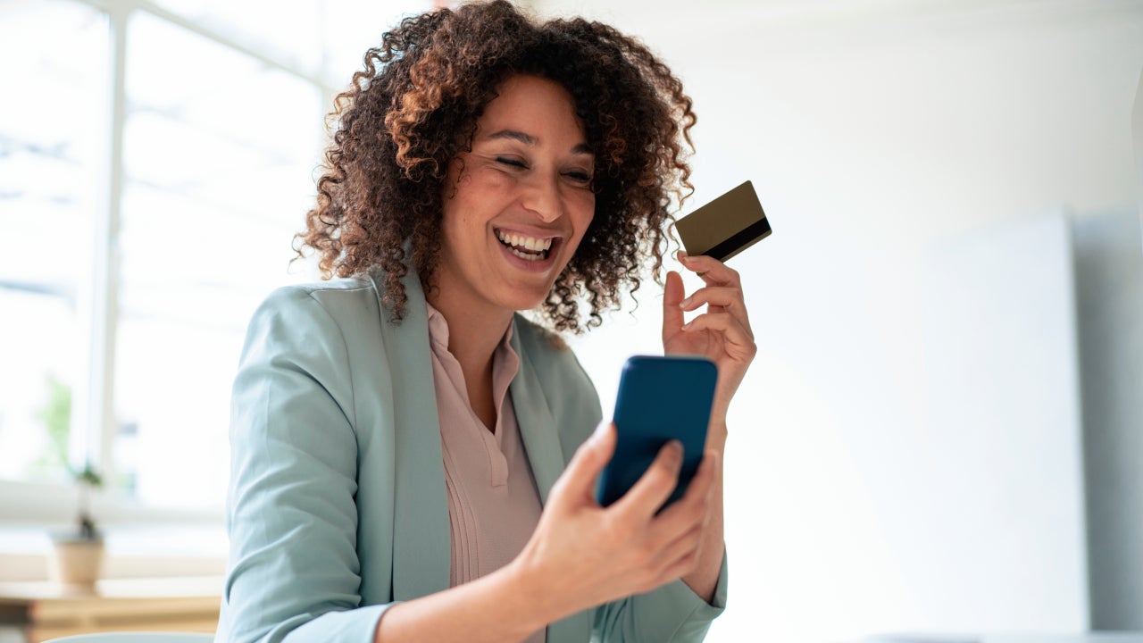 Happy businesswoman doing online payment through smart phone at workplace
