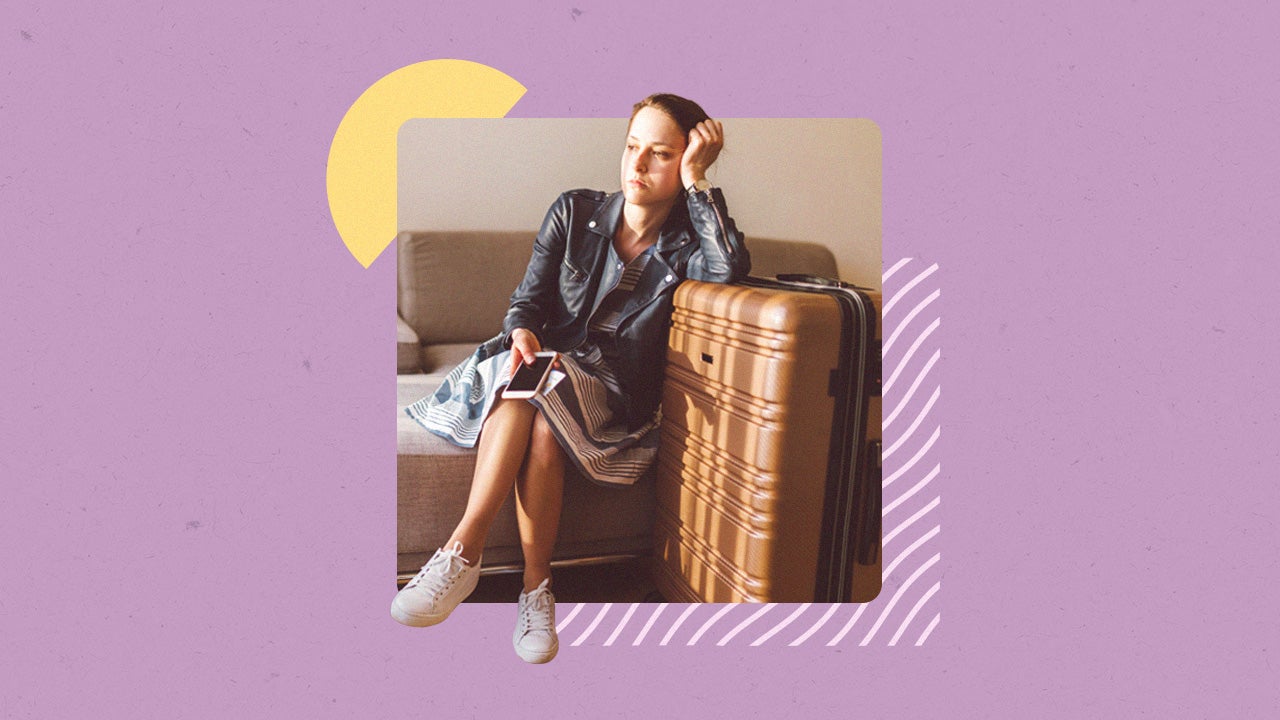 Young forlorn woman sitting down with a suitcase packed