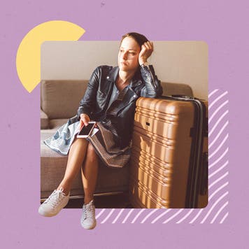 Young forlorn woman sitting down with a suitcase packed