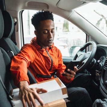 Young male driver using smart phone while sitting in delivery van