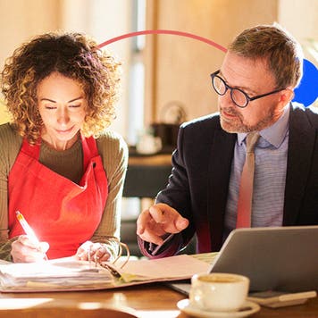 Female business owner and financial advisor review documents in a coffee shop.