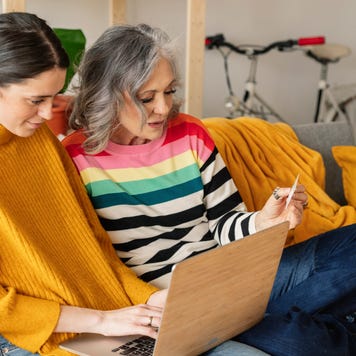 Daughter and mother shopping online with credit card on laptop