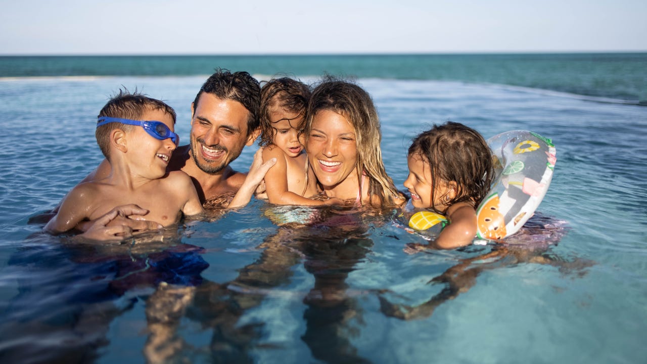 Happy parents and their kids enjoying in the swimming pool.