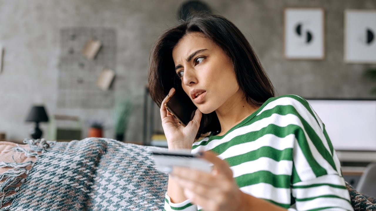 Concerned lady talking on smartphone having finance stolen from card