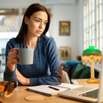 young woman sitting in her living room, working from home using her laptop