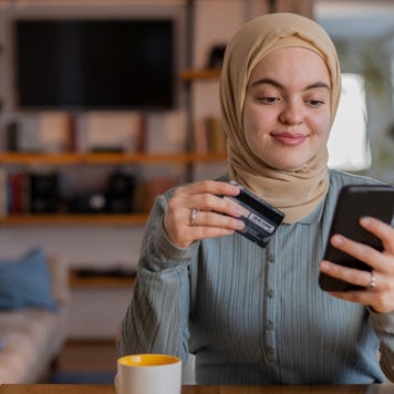 Woman holding credit card and shopping on phone