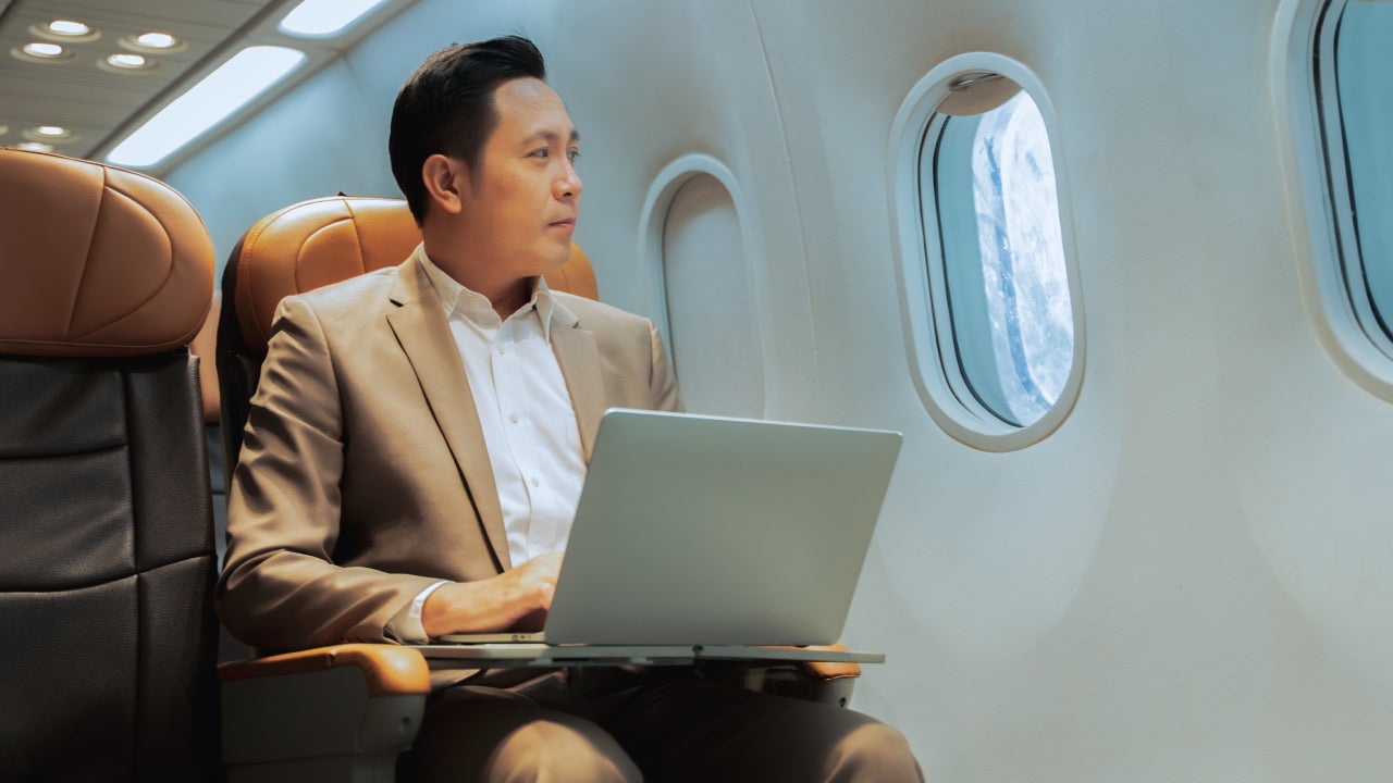 Businessman with notebook sitting inside an airplane.