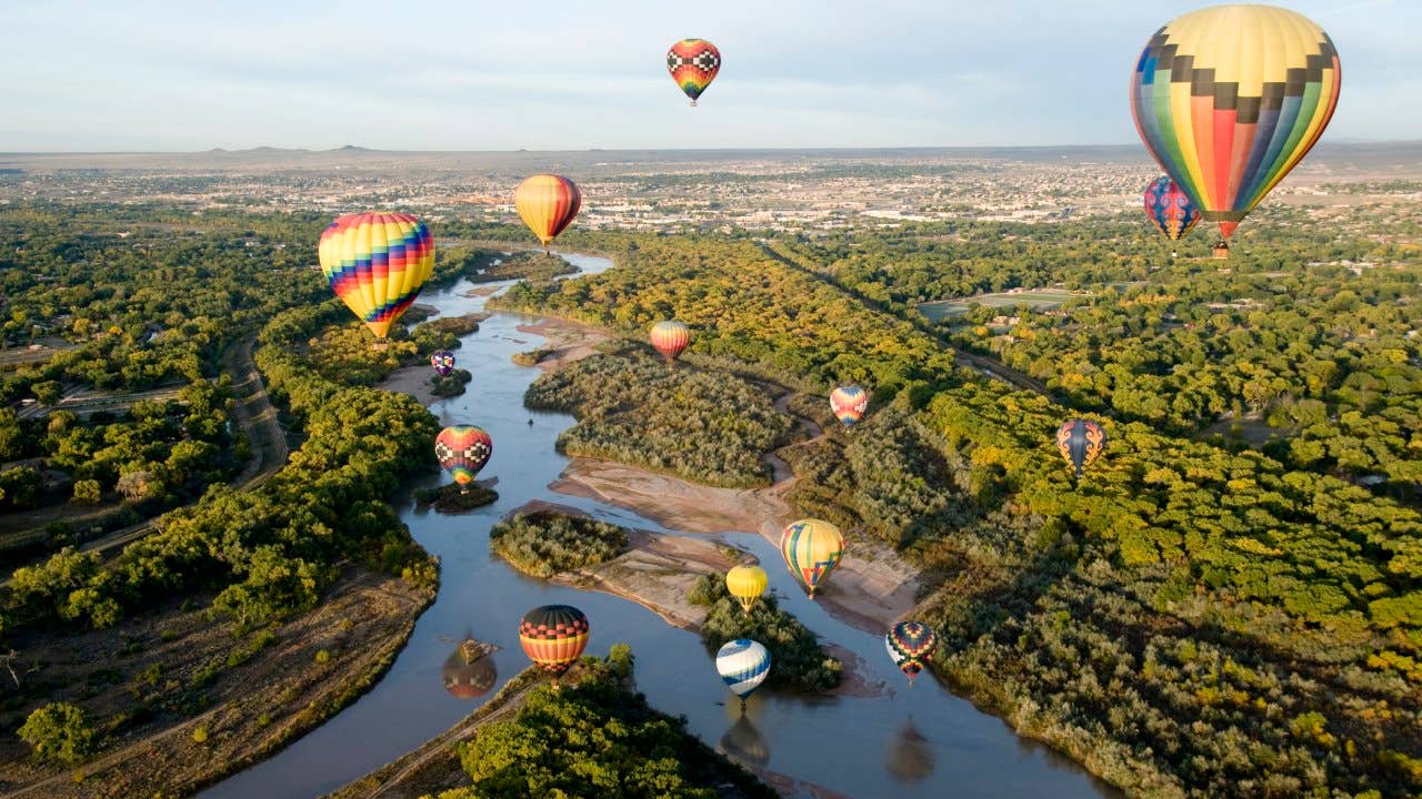 Hot air balloons drifting over the Rio Grande river in Albuquerque, New Mexico.