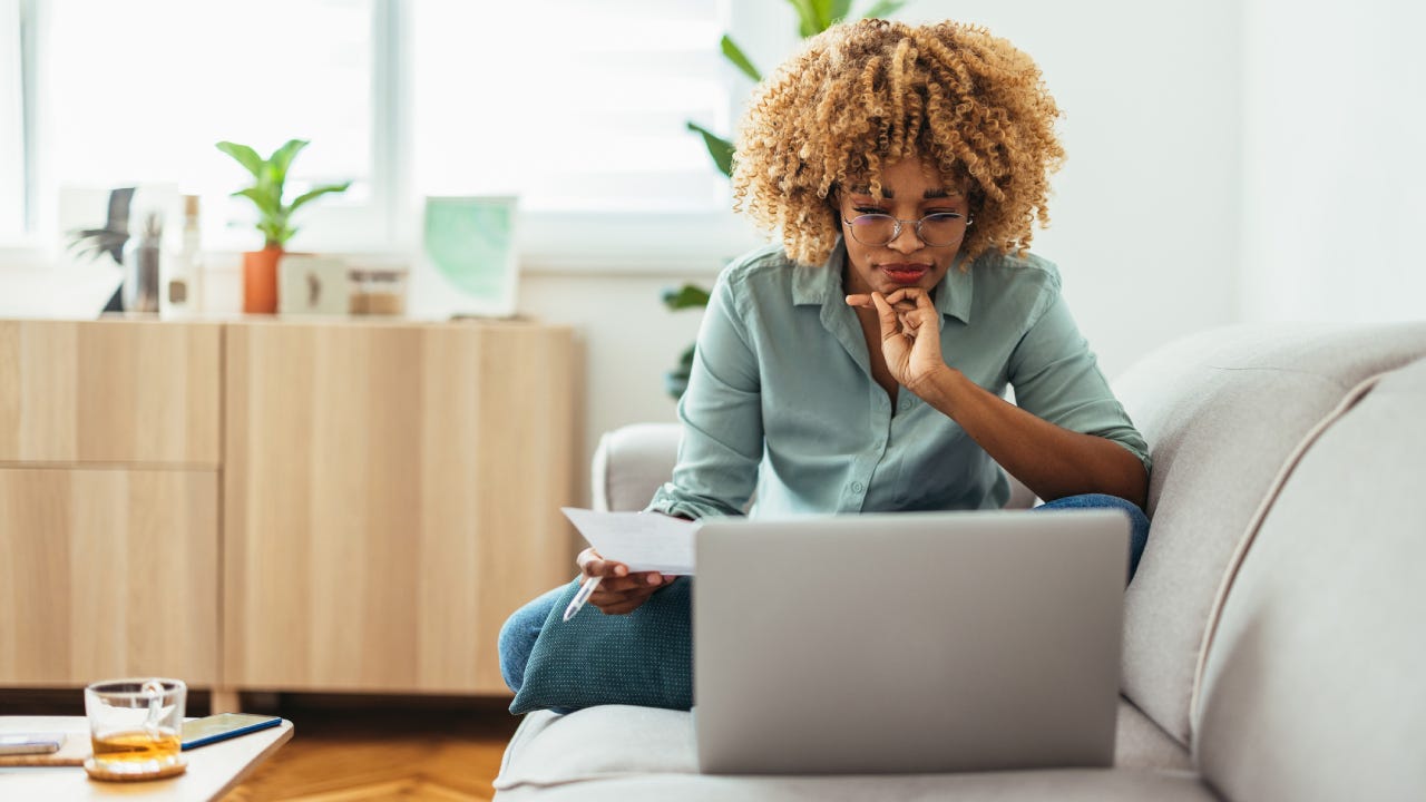 Person working on a computer on an office couch and drinking tea