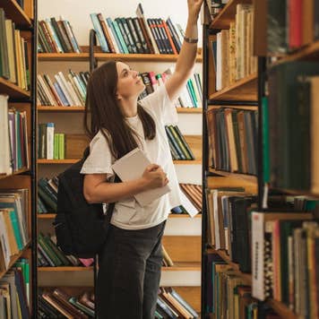 Portrait of female student looking for special book