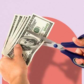 Someone cutting a stack of cash with scissors