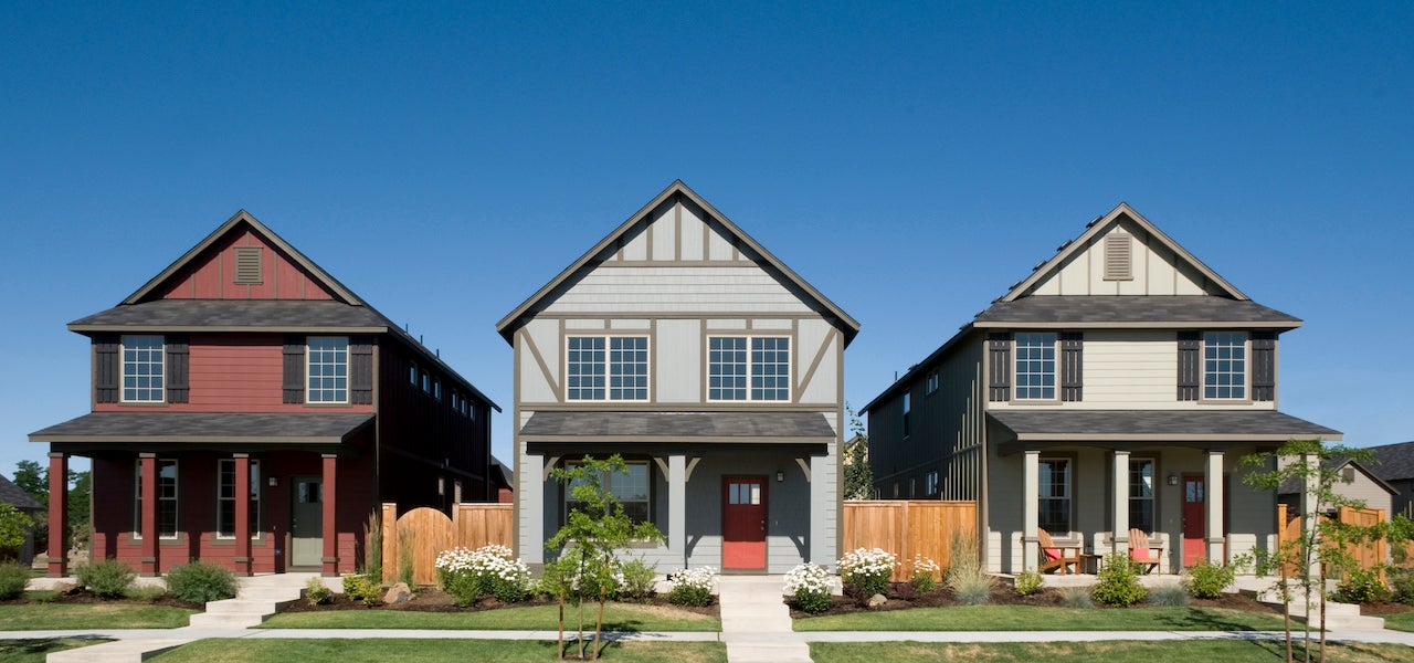 three modest suburban homes with front porches and blue sky