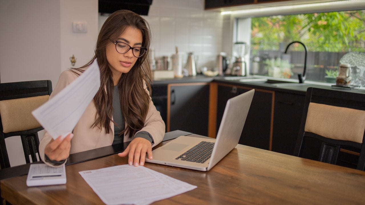 Young woman using calculator while going through bills and home finances