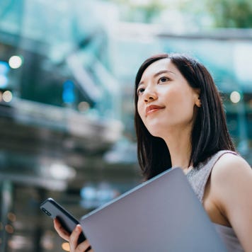 businesswoman carrying smartphone and laptop, commuting to work