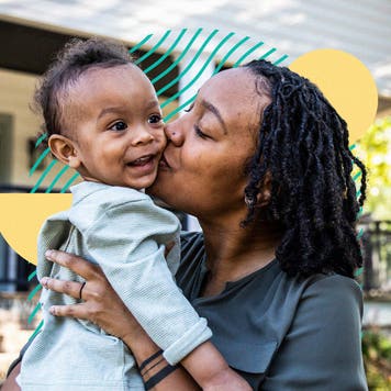 Woman kissing baby outside of house