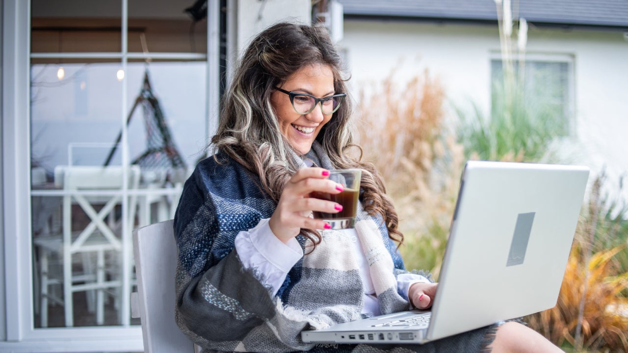 A young woman is drinking coffee in the garden of her house